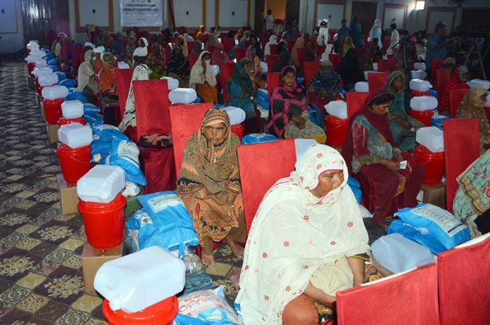 Flood-affected households sitting with their essential relief packages during a distribution ceremony at a local hall in Union Council Sher Shah, organized by the Farmer Development Organization in collaboration with the Pakistan Poverty Alleviation Fund