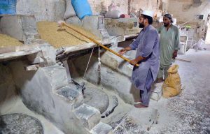 A worker strains wheat in a local mill at Warsak Road before crushing