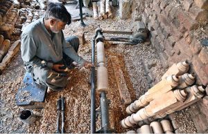 A carpenter skillfully carves designs on the pieces of traditional wooden bed "Charpai" at his workplace.