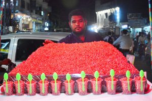A vendor displays freshly served red pomegranate seeds in disposable glasses with spoons on his handcart to attract customers at Gul Center