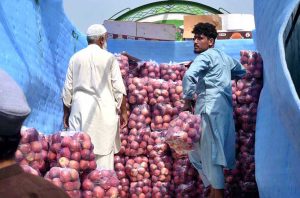 Laborers offload packets of apples from a delivery truck at Fruit Mandi near Hashtnagri.