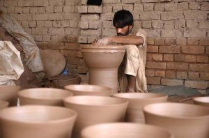 A porter skillfully molding traditional clay pots at his work place in Phandu area.