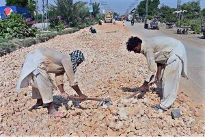 Labourers are busy in construction work of Autobahn Road during development work in the city.