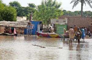 Flood-affected villagers wait for rescuers outside their flooded homes to move families and belongings from flood hit area.