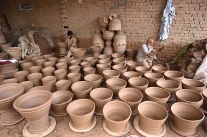 A porter skillfully molding traditional clay pots at his work place in Phandu area.