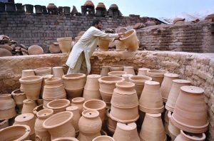 A porter skillfully molding traditional clay pots at his work place in Phandu area.