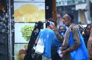 A street vendor sprays bubbles into the air with bubble guns to attract children at Clock Tower Chowk.