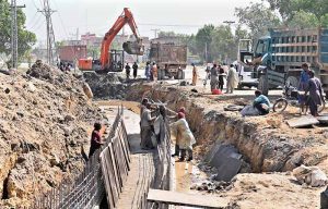 Laborers are busy constructing a sewage drain (nala) with heavy machinery on Autobahn Road during the city's development work.