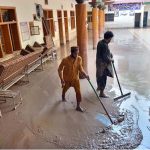 People clear mud outside their damaged school after deadly floods hit the build in the Budni Pul area