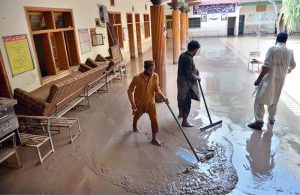 People clear mud outside their damaged school after deadly floods hit the build in the Budni Pul area