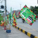 A vendor displays religious flags and badges at a roadside stall in connection with Rabi-ul-Awal celebrations