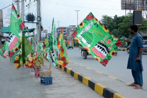 A vendor displays religious flags and badges at a roadside stall in connection with Rabi-ul-Awal celebrations