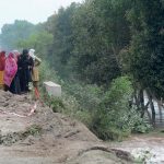 Women watching helplessly as their houses are swallowed by floodwater after fresh flash floods hit Village Kalri, Tehsil Bhuwana Lalian Road, near River Chenab, displacing thousands and disrupting daily life