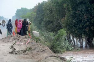Women watching helplessly as their houses are swallowed by floodwater after fresh flash floods hit Village Kalri, Tehsil Bhuwana Lalian Road, near River Chenab, displacing thousands and disrupting daily life