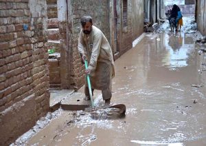 People clear mud outside their damaged school after deadly floods hit the build in the Budni Pul area