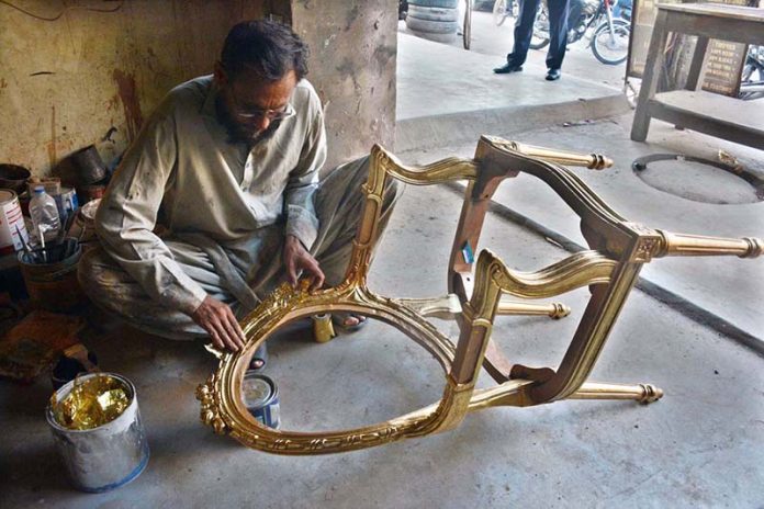 A carpenter makes a fancy chair in Saddar