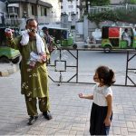 An elderly vendor making bubbles to attract children at a local market
