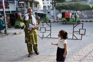 An elderly vendor making bubbles to attract children at a local market