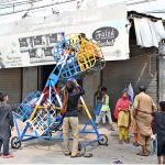 Children enjoy a ride on a portable mini sky wheel swing after paying to swings seller in Jinnah Colony