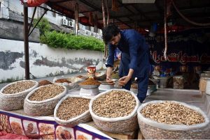 An elderly vendor making bubbles to attract children at a local market