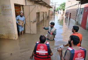 Rescue 1122 personnel use life-saving boats to evacuate residents stranded in rising floodwaters after a deadly flood hit the Budni area.
