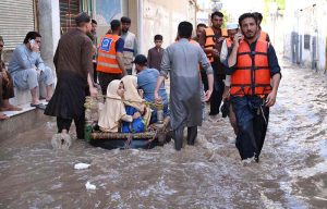 Rescue 1122 personnel use life-saving boats to evacuate residents stranded in rising floodwaters after a deadly flood hit the Budni area.