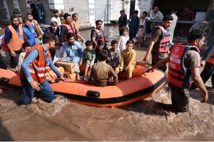 Rescue 1122 personnel use life-saving boats to evacuate residents stranded in rising floodwaters after a deadly flood hit the Budni area.