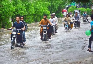 A rickshaw passes through rainwater accumulated near Shehbaz Building after heavy rain.