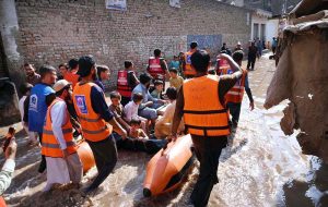 Rescue 1122 personnel use life-saving boats to evacuate residents stranded in rising floodwaters after a deadly flood hit the Budni area.