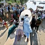 Residents help move a boat to rescue stranded families in flood-hit areas