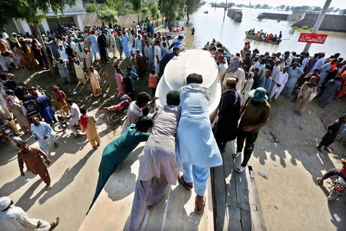 Residents help move a boat to rescue stranded families in flood-hit areas