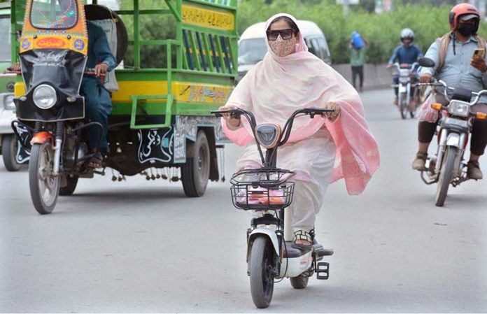 A woman confidently drives her electric Scooty on Millat Road, part of a growing trend of women embracing personal transport