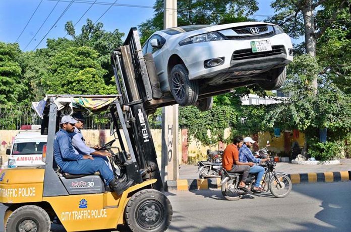 City Traffic Police personnel are using lifters to remove illegally parked vehicles from the road