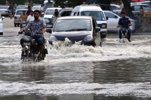 Vehicles and commuters struggle to navigate a heavily flooded road in Scheme 33 near Gulshan-e-Kaneez Fatima Society after torrential rains lashed the city