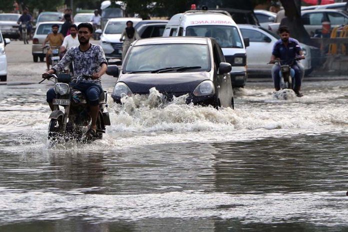 Vehicles and commuters struggle to navigate a heavily flooded road in Scheme 33 near Gulshan-e-Kaneez Fatima Society after torrential rains lashed the city
