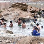 Children enjoy bathing in rainwater accumulated after recent downpours