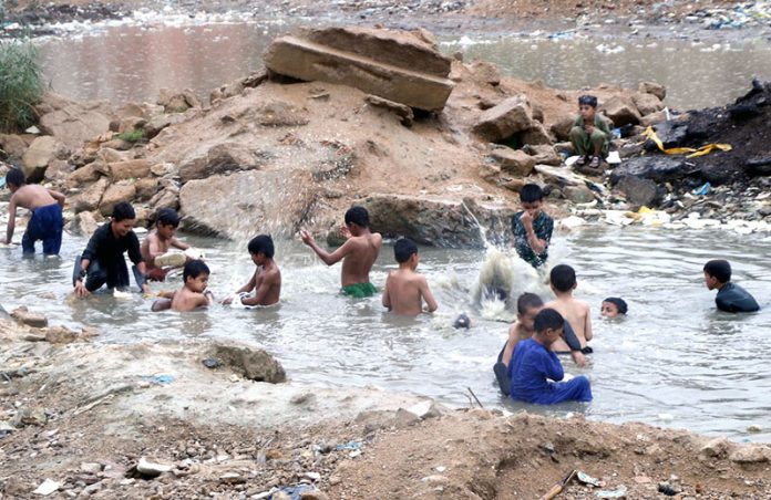 Children enjoy bathing in rainwater accumulated after recent downpours