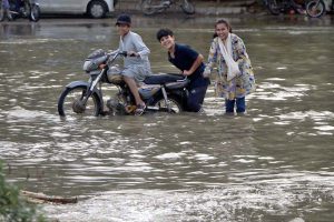 Vehicles and commuters struggle to navigate a heavily flooded road in Scheme 33 near Gulshan-e-Kaneez Fatima Society after torrential rains lashed the city