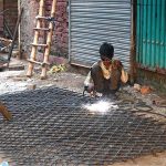 A young labourer welds an iron grill for customers outside a shop in the provincial capital