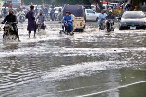 Vehicles and commuters struggle to navigate a heavily flooded road in Scheme 33 near Gulshan-e-Kaneez Fatima Society after torrential rains lashed the city