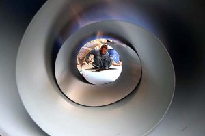 An ironsmith cuts a stainless steel sheet outside his workplace in the provincial capital