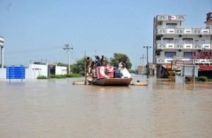 Residents transport goods on a boat through flooded streets after the River Sutlej overflowed, submerging residential and commercial areas.