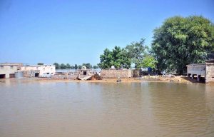Residents transport goods on a boat through flooded streets after the River Sutlej overflowed, submerging residential and commercial areas.