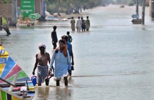 People wade through floodwater after the River Sutlej overflowed, inundating low-lying areas.
