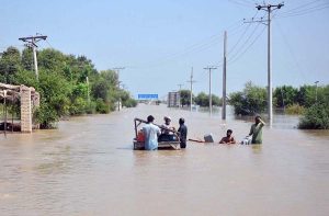 People wade through floodwater after the River Sutlej overflowed, inundating low-lying areas.