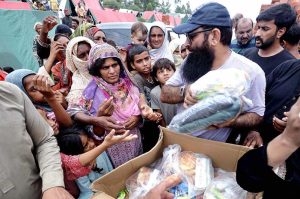 A volunteer distributes food and essential items to flood-affected victims outside a makeshift relief camp built on high ground in a flooded area on the outskirts of the Provincial Capital.