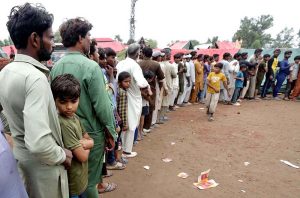 A volunteer distributes food and essential items to flood-affected victims outside a makeshift relief camp built on high ground in a flooded area on the outskirts of the Provincial Capital.
