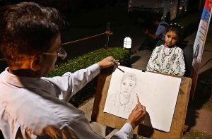 An artist sketching a girl’s portrait at Port Grand.
