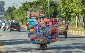 A vendor riding his motorcycle loaded with household plastic items on the way in the city.