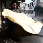 A vendor busy preparing large Manda Roti (Rumali Roti) and Samosa Patti at his roadside setup in Ghori Town.